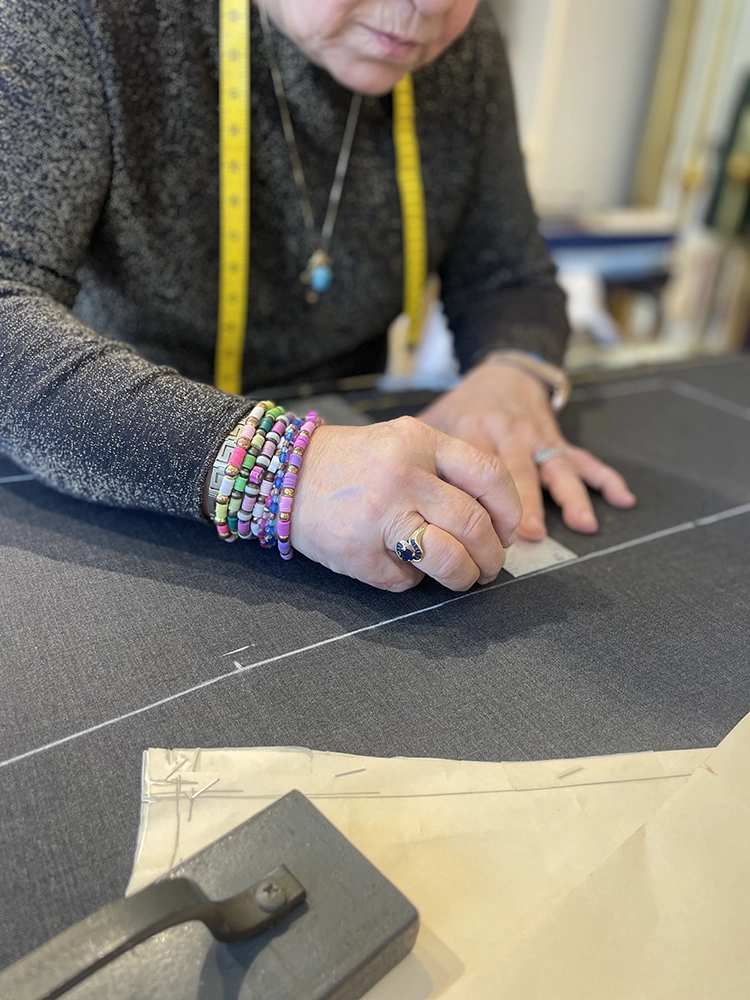 A cutter drafting a pattern by hand on the atelier table